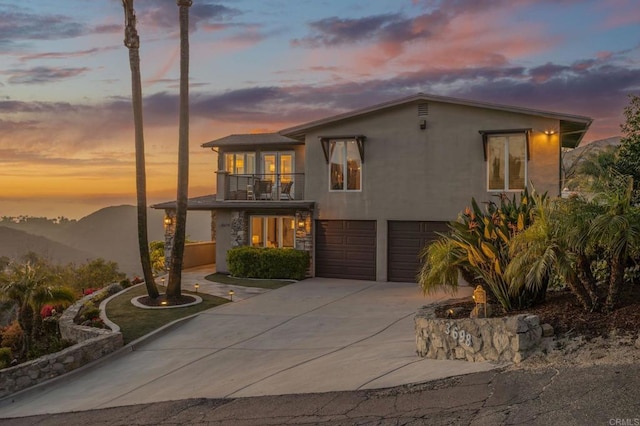 view of front of home featuring a balcony, stucco siding, an attached garage, and concrete driveway