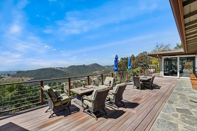 wooden terrace with outdoor dining space and a mountain view