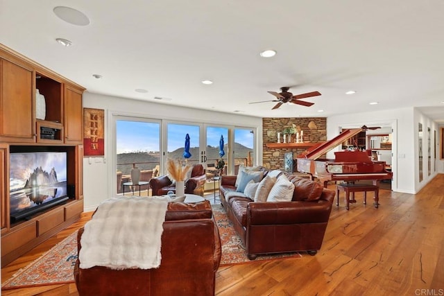 living area with light wood-type flooring, a ceiling fan, and recessed lighting
