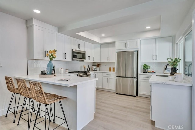 29461 Via Valverde, Laguna Niguel, CA 92677 - kitchen featuring decorative backsplash, a peninsula, appliances with stainless steel finishes, and a raised ceiling