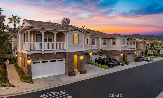 view of front facade featuring concrete driveway, a balcony, stone siding, and a garage