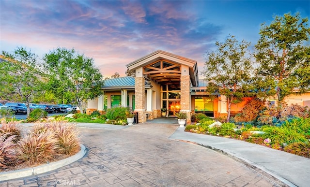 view of front of property featuring stucco siding, metal roof, stone siding, and a standing seam roof