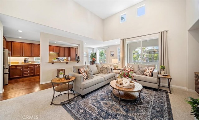 living area featuring baseboards, recessed lighting, a towering ceiling, and wood finished floors