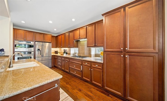 kitchen featuring light stone countertops, dark wood-type flooring, recessed lighting, a sink, and appliances with stainless steel finishes