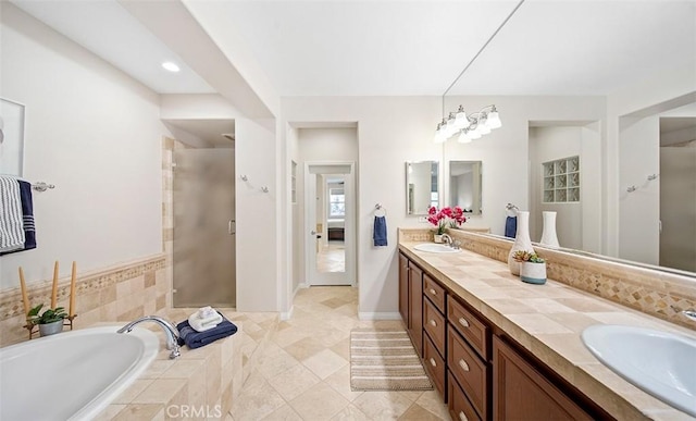 full bath featuring double vanity, a sink, a garden tub, and a stall shower