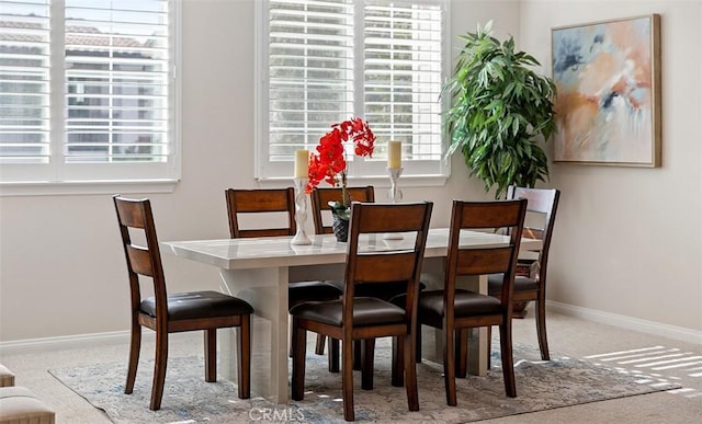 carpeted dining space featuring baseboards and a healthy amount of sunlight