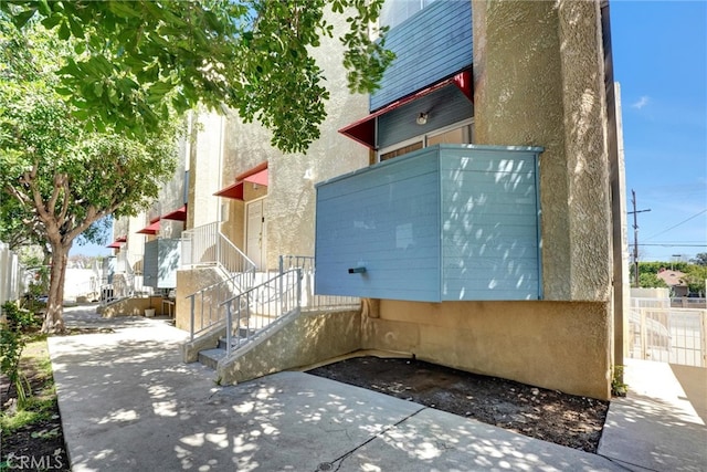 view of property exterior with fence, stucco siding, and a patio area