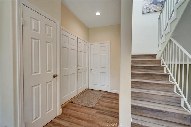 entrance foyer with recessed lighting, wood finished floors, and stairway