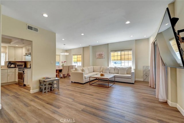 living room featuring visible vents, a healthy amount of sunlight, and light wood-type flooring