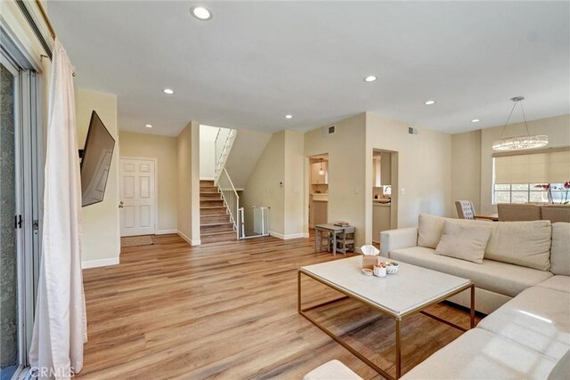 living area featuring an inviting chandelier, baseboards, stairway, light wood-type flooring, and recessed lighting