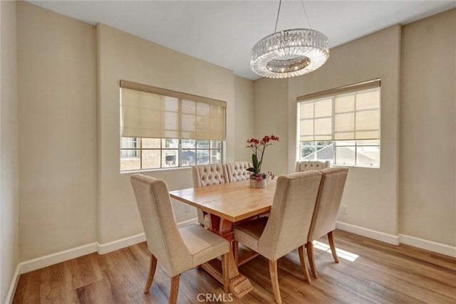 dining area with plenty of natural light, baseboards, wood finished floors, and a notable chandelier