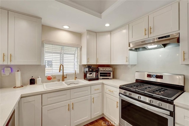 kitchen featuring a sink, under cabinet range hood, stainless steel gas stove, and white cabinetry