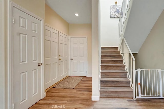 stairs with baseboards, recessed lighting, and wood finished floors