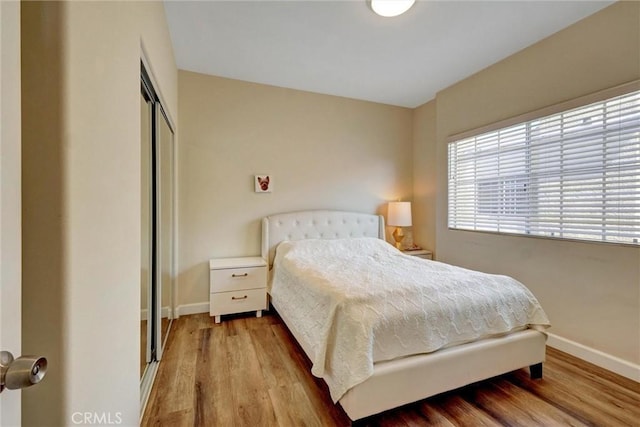 bedroom with baseboards, wood finished floors, and a closet