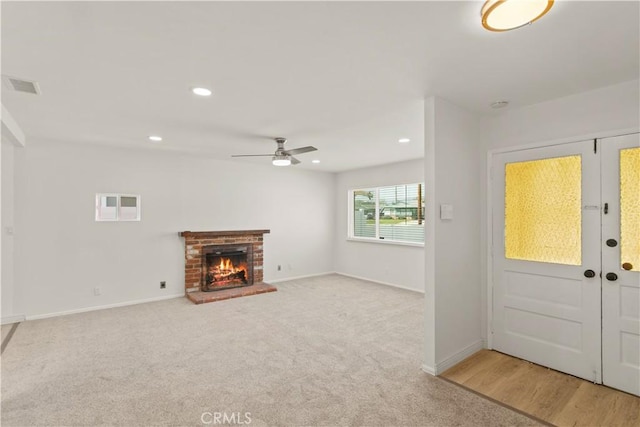 foyer featuring a fireplace, visible vents, baseboards, and ceiling fan