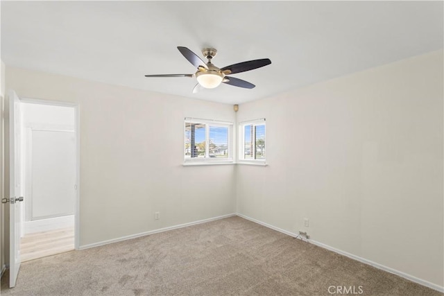 carpeted spare room with ceiling fan and baseboards