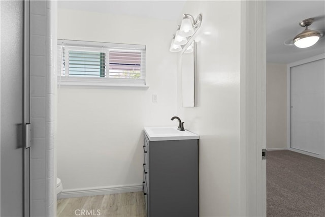 bathroom featuring toilet, vanity, and baseboards