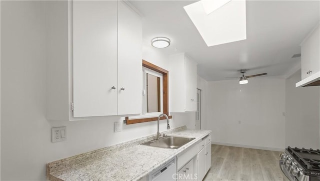 kitchen featuring stainless steel range with gas cooktop, white cabinets, a skylight, dishwasher, and a sink