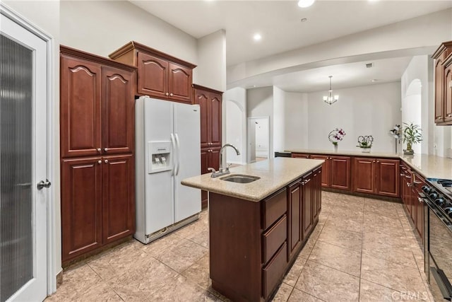 11076 Yuba Rd, Phelan, CA 92371 - kitchen featuring white fridge with ice dispenser, light stone countertops, a kitchen island with sink, black gas range oven, and recessed lighting