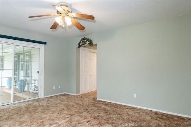 carpeted empty room featuring a ceiling fan and baseboards