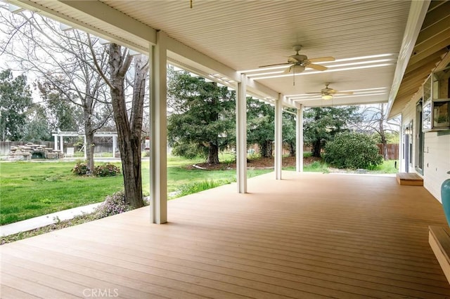 wooden terrace with a ceiling fan and a yard