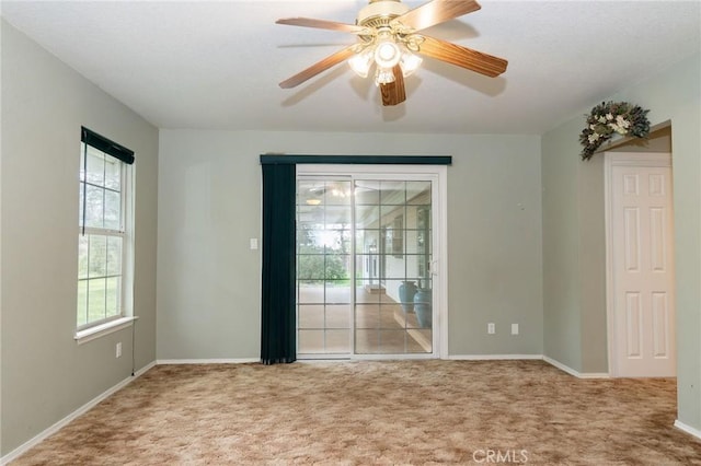empty room with baseboards, ceiling fan, and carpet