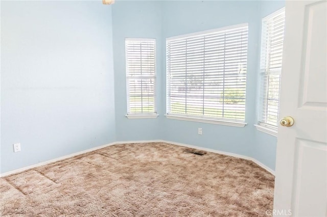 carpeted empty room featuring visible vents and baseboards