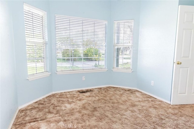 carpeted spare room featuring visible vents and baseboards