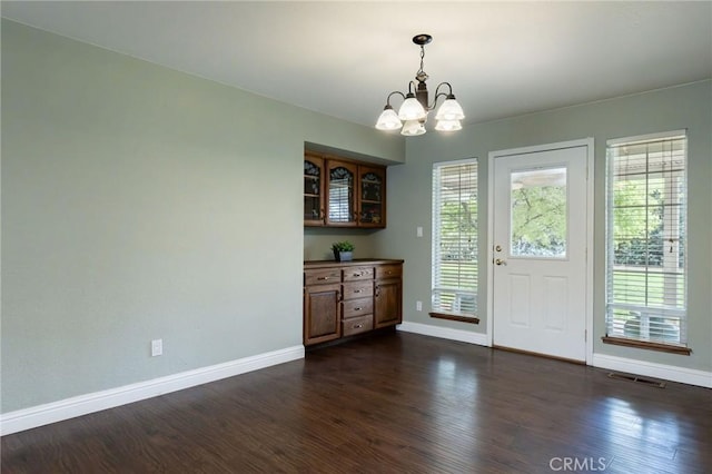 unfurnished dining area with baseboards, a notable chandelier, and a wealth of natural light