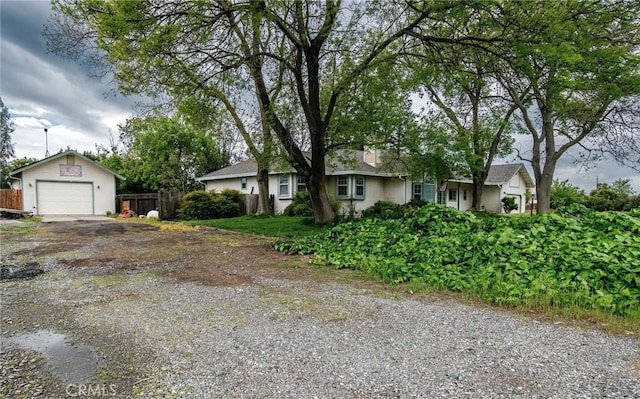 ranch-style house with an outdoor structure, a detached garage, driveway, and fence