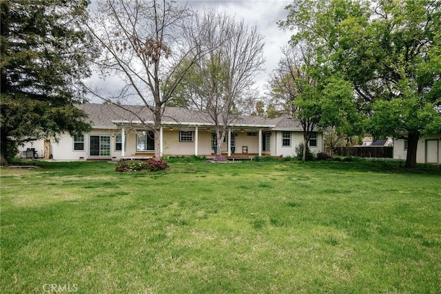 back of property featuring covered porch and a yard