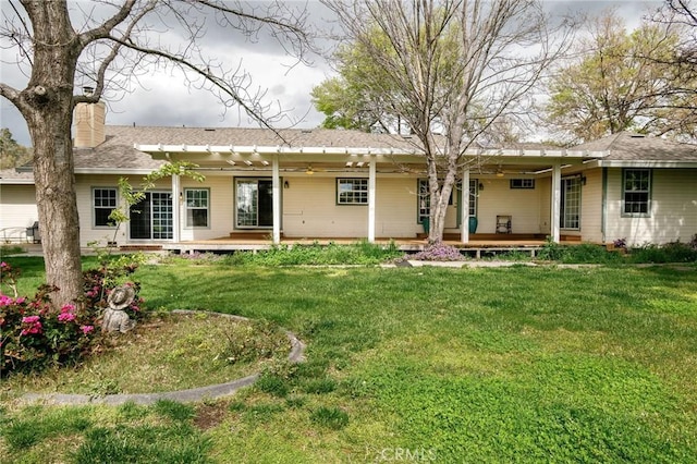 back of house with a chimney, ceiling fan, a porch, and a yard