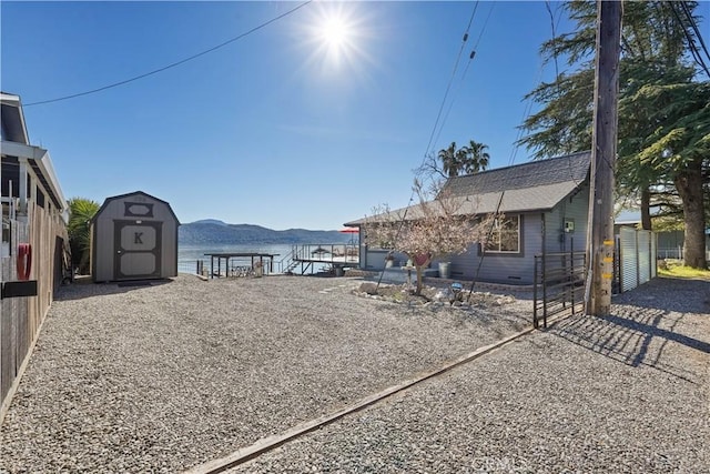 view of yard featuring a storage unit, an outbuilding, fence, and a mountain view