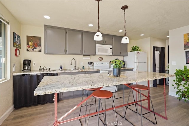 kitchen with recessed lighting, light wood finished floors, a sink, white appliances, and baseboards