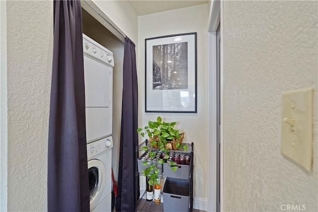 washroom featuring a textured wall, stacked washer and clothes dryer, and laundry area