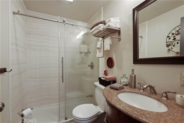 bathroom featuring a textured wall, vanity, a shower stall, and toilet