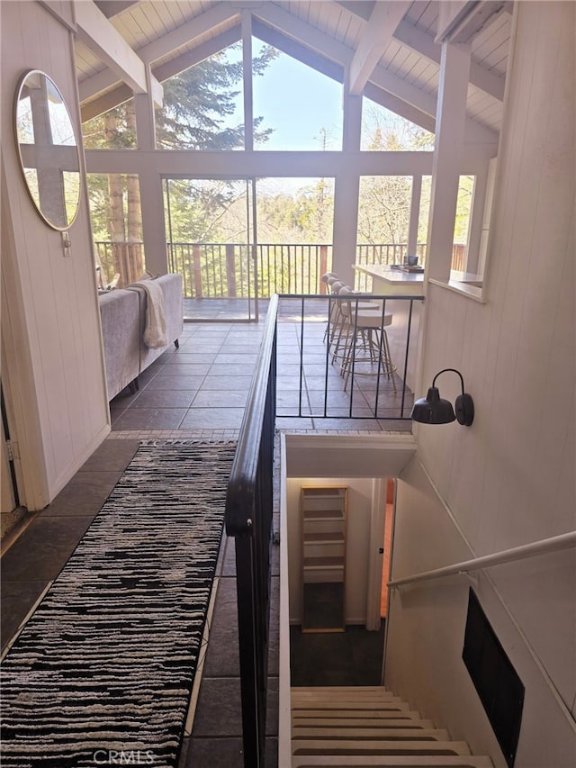 stairs featuring wood walls and lofted ceiling with beams