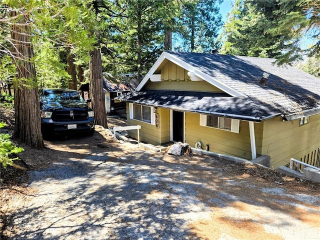 view of front facade featuring driveway, roof with shingles, and board and batten siding