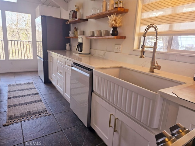 kitchen with freestanding refrigerator, open shelves, white cabinets, dishwasher, and a sink