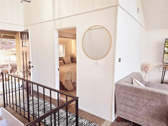 hallway featuring tile patterned flooring, high vaulted ceiling, and baseboards
