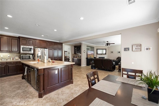 3274 Rural Ln, Corona, CA 92882 - kitchen featuring light countertops, crown molding, dark brown cabinets, appliances with stainless steel finishes, and an island with sink