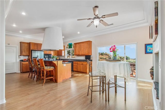 kitchen featuring stainless steel fridge with ice dispenser, black microwave, crown molding, a kitchen island, and brown cabinetry