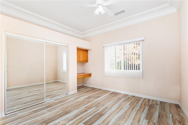 unfurnished bedroom featuring a closet, light wood finished floors, baseboards, and ornamental molding