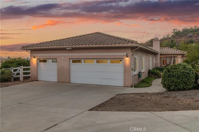 exterior space with driveway, stucco siding, a tiled roof, and an attached garage