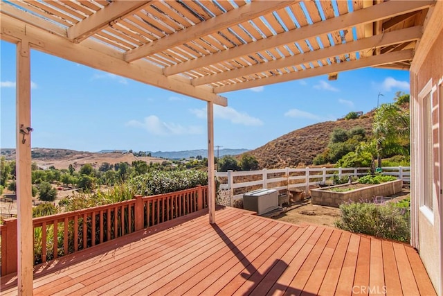 wooden deck featuring a mountain view, a pergola, fence, and a vegetable garden