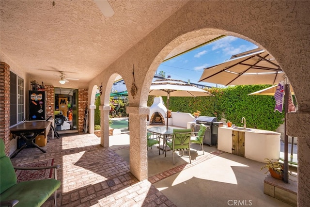 view of patio featuring outdoor dining space, exterior kitchen, grilling area, a ceiling fan, and a sink