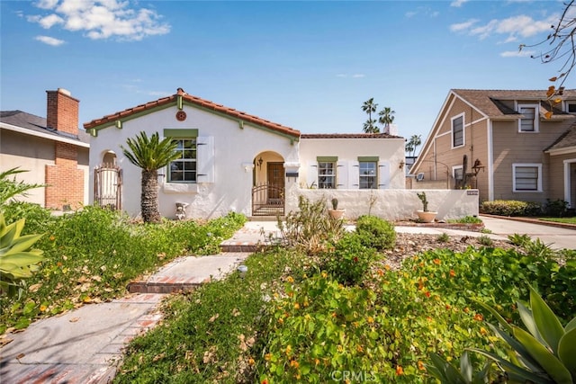 mediterranean / spanish home with stucco siding, fence, and a chimney