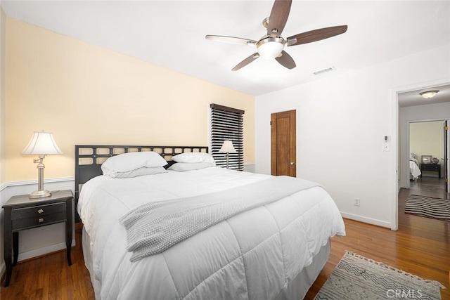 bedroom featuring wood finished floors, baseboards, a ceiling fan, and visible vents