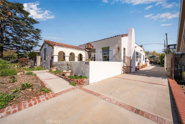 mediterranean / spanish home featuring a fenced front yard and stucco siding