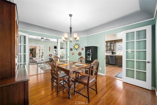 dining room featuring baseboards, ornamental molding, wood finished floors, ceiling fan with notable chandelier, and french doors